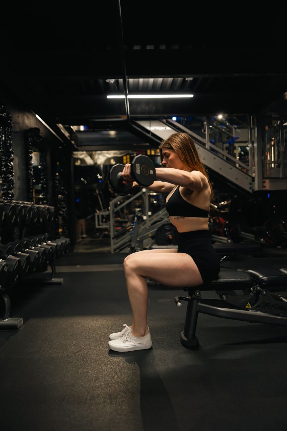 Madison performing a seated dumbbell lateral raise